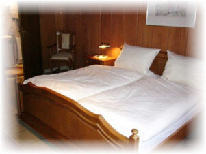 Hotel & Appartements Klostermannの木製家具とダブルベッドのある居心地の良いベッドルーム。