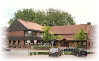 Hotel & Appartements Klostermannの外観。建物の前に赤い瓦屋根、木々、数台の駐車車両。