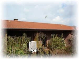 曇り空の下、赤い屋根と緑の庭を持つホテル＆アパートメント・クロスターマンの外観。