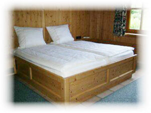 Hotel & Appartements Klostermannの木製ベッドと白いベッドリネンのシンプルなダブルルームは、居心地の良い雰囲気です。