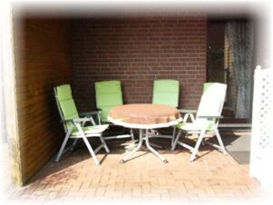 Hotel & Appartements Klostermannの緑色の椅子4脚と茶色のテーブルクロスのかかったテーブルのあるテラスエリア。