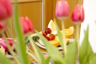 Gros plan de fruits frais et de tulipes roses sur une table de la Pension Garni Zweck, convenant &agrave; un buffet de petit-d&eacute;jeuner bienvenu.