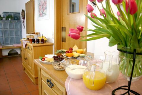 Petit d&eacute;jeuner buffet avec fruits frais, jus de fruits et yaourts dans une salle confortable de la Pension Garni Zweck d&eacute;cor&eacute;e de tulipes.