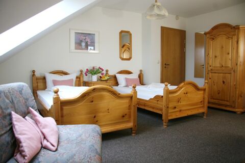Two single wooden beds with white bedding and pillows in a room at Pension Garni Zweck with a wardrobe and sofa