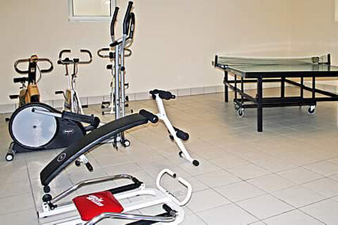 Innenraum mit Fitnessger&auml;ten und einem Tischtennistisch im Freizeitraum der Ferienwohnungen G&auml;stehaus Therme-Blick.