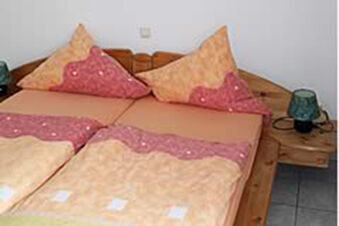 Gem&uuml;tliches Schlafzimmer mit Doppelbett und passenden Kissen im Ferienwohnungen G&auml;stehaus Therme-Blick in harmonischen Farben.