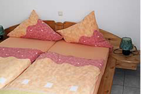 Gem&uuml;tliches Schlafzimmer mit Doppelbett und passenden Kissen im Ferienwohnungen G&auml;stehaus Therme-Blick in harmonischen Farben.