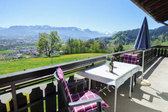 Balcony at Bauernhof Ferienhof K&uuml;hberg with table, two chairs, an umbrella, and distant view of mountains and village