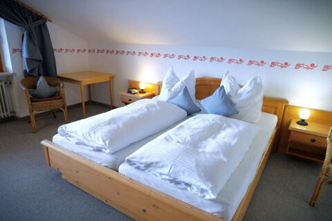 Double bed with white bedding and blue pillows in a wooden frame room at Bauernhof Ferienhof K&uuml;hberg with side tables and lamps