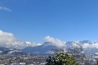 Snowy mountain landscape under a clear blue sky with trees and the town below near Bauernhof Ferienhof K&uuml;hberg