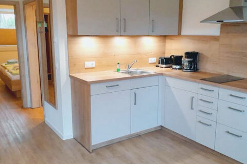 Modern kitchen with white cabinets, wooden countertops, built-in stove, sink, coffee maker, and toaster at Fewos Haus am W&auml;ldchen