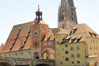 Saat kuleli ve taş &ccedil;atılı tarihi bina, g&uuml;n ışığında eski şehir ortamında Hotel-Caf&eacute; 3 Kronen'in cephesi.