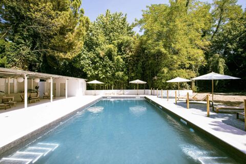 Outdoor swimming pool with white umbrellas and lounge chairs surrounded by green trees at B&B Hotel Mantova Cristallo