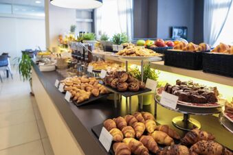 Breakfast buffet featuring croissants, muffins, cookies, fruit, and various pastries at B&B Hotel Mantova Cristallo dining area