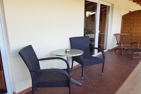 Two black wicker chairs and a small round metal table on a tiled balcony at Land-gut-Hotel Seeblick