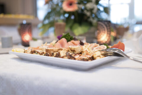 A white rectangular plate with assorted sliced meats and cheese on a white tablecloth at Land-gut-Hotel Seeblick