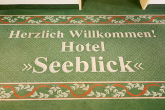 Green carpet with white text "Herzlich Willkommen! Hotel Seeblick" surrounded by decorative leaf patterns for Land-gut-Hotel Seeblick