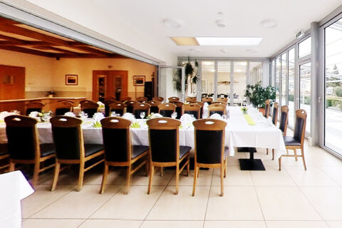 Dining room at Land-gut-Hotel Seeblick with wooden chairs arranged around tables set with white tablecloths and glassware