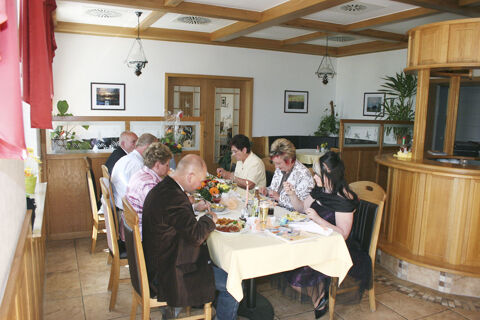 Seven people sitting around a table with food and drinks inside a restaurant at Land-gut-Hotel Seeblick