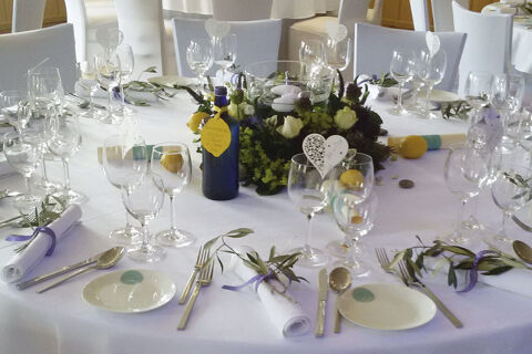 Round table set with white linens, glassware, plates, silverware, floral centerpiece, and bottles at Land-gut-Hotel Seeblick