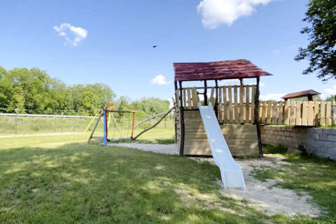 Children's playground with a slide, swings, and climbing structures in a grassy area at Land-gut-Hotel Seeblick