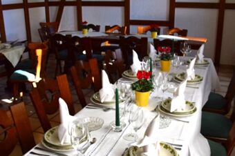 Den festligt inredda matsalen p&aring; Gasthof Pension R&ouml;per-Bolte med vita dukar, blommor och elegant arrangerade bestick.