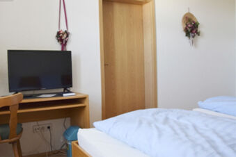 Enkelt inredda hotellrum med s&auml;ng, TV och tr&auml;m&ouml;bler i Gasthof Pension R&ouml;per-Bolte f&ouml;r en avkopplande vistelse.