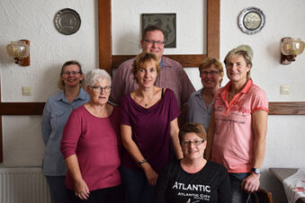 Sex personer st&aring;r och sitter i ett rum med en vit v&auml;gg p&aring; pensionatet R&ouml;per-Bolte, en v&auml;nlig gruppbild i en mysig atmosf&auml;r.