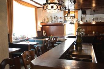 Mysigt g&auml;strum med tr&auml;m&ouml;bler och dekorativa lampor i Gasthof Pension R&ouml;per-Bolte, typisk lantlig atmosf&auml;r med naturligt ljus.