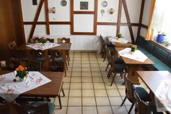 Mysig matsal med tr&auml;m&ouml;bler och traditionella dekorationer i Gasthof Pension R&ouml;per-Bolte, med dukade bord och blomsterarrangemang.