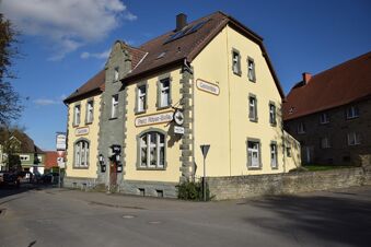 Den gulm&aring;lade fasaden p&aring; pensionatet R&ouml;per-Bolte med pensionatets skylt under en solig himmel p&aring; en lugn gata.
