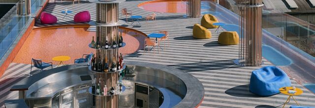 Outdoor bar area at Nhow Milano with colorful tables, chairs, bean bags, and a circular pool surrounding the bar