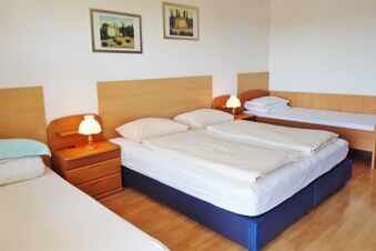Drei Betten mit Holzkopfteilen, Nachttischen mit Lampen und zwei Bilder an der Wand in einem gem&uuml;tlichen Zimmer im Hotel Pension Heigl.