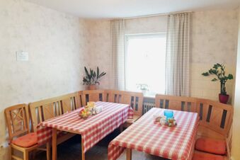 Gem&uuml;tlicher Essbereich mit Eckbank, Holzst&uuml;hlen und karierten Tischdecken im Hotel Pension Heigl, ideal f&uuml;r Fr&uuml;hst&uuml;ck oder Zusammenk&uuml;nfte.