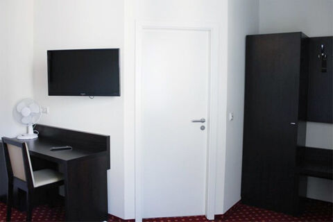 Jednodu&scaron;e zař&iacute;zen&yacute; hotelov&yacute; pokoj s psac&iacute;m stolem, TV a &scaron;atn&iacute; skř&iacute;n&iacute; v hotelu Aariana, modern&iacute; a funkčn&iacute; design.