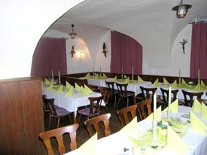 Dining area at Gasthaus Berger with white tablecloths, yellow napkins folded on tables, wooden chairs, and arched ceilings