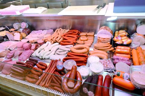 Прилавок с большим выбором различных колбас и холодных закусок Gasthof Br&auml;uwirt, представленных в стеклянной витрине.