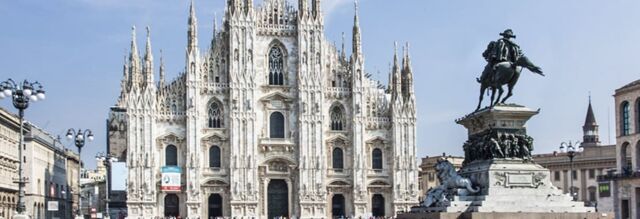 White ornate Gothic cathedral with multiple spires and a large equestrian statue in the foreground near NH Hotel Linate