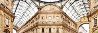 Glass ceiling and ornate stone architecture of a historic covered gallery with detailed frescoes at NH Hotel Linate interior