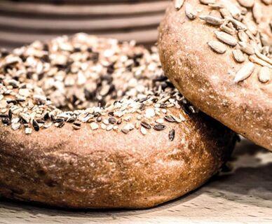Nahaufnahme von zwei mit K&ouml;rnern bestreuten Bagels als Teil des Fr&uuml;hst&uuml;cksangebots im Hotel Frisch.