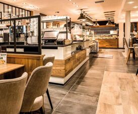Moderner und gem&uuml;tlicher Fr&uuml;hst&uuml;cksbereich im Hotel Frisch mit Holz- und Fliesenelementen sowie einem Buffet und komfortablen Sitzgelegenheiten.