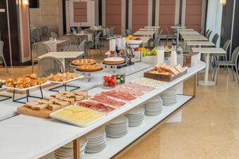 Breakfast buffet with various breads, pastries, sliced meats, cheeses, fruit, and cereals at B&B Hotel San Mauro dining area