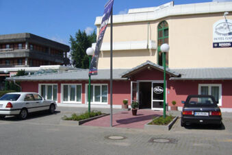 Hotel Garni Stadt Friedberg building with beige and red walls, two cars parked outside, and entrance with open glass door