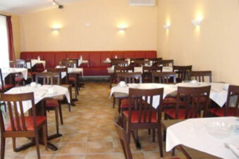 Dining area of Hotel Garni Stadt Friedberg with multiple tables, wooden chairs, white tablecloths, and wall lights