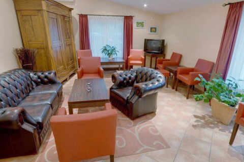Hotel Garni Stadt Friedberg lounge with leather sofas, orange chairs, coffee tables, potted plants, and TV on wooden stand