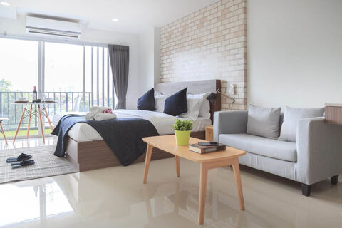 Modern hotel room at Hotel Garni Stadt Friedberg with a bed, sofa, coffee table, balcony, and natural light through sliding doors