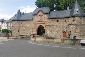 Stone medieval gatehouse with arched entrance and slate roof, part of Hotel Garni Stadt Friedberg building facade