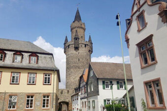 Stone tower with conical roof behind historical European-style buildings on clear day near Hotel Garni Stadt Friedberg