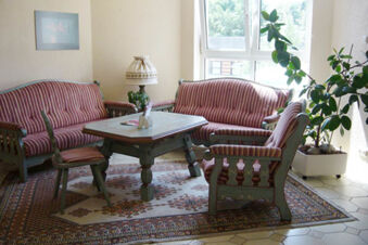 Living room seating with striped cushions around a wooden table on a patterned rug at Hotel Garni Stadt Friedberg