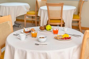Breakfast table with glasses of juice, coffee cups, plates with bread, fruit, and pastries in B&B Hotel Bergamo Executive dining area